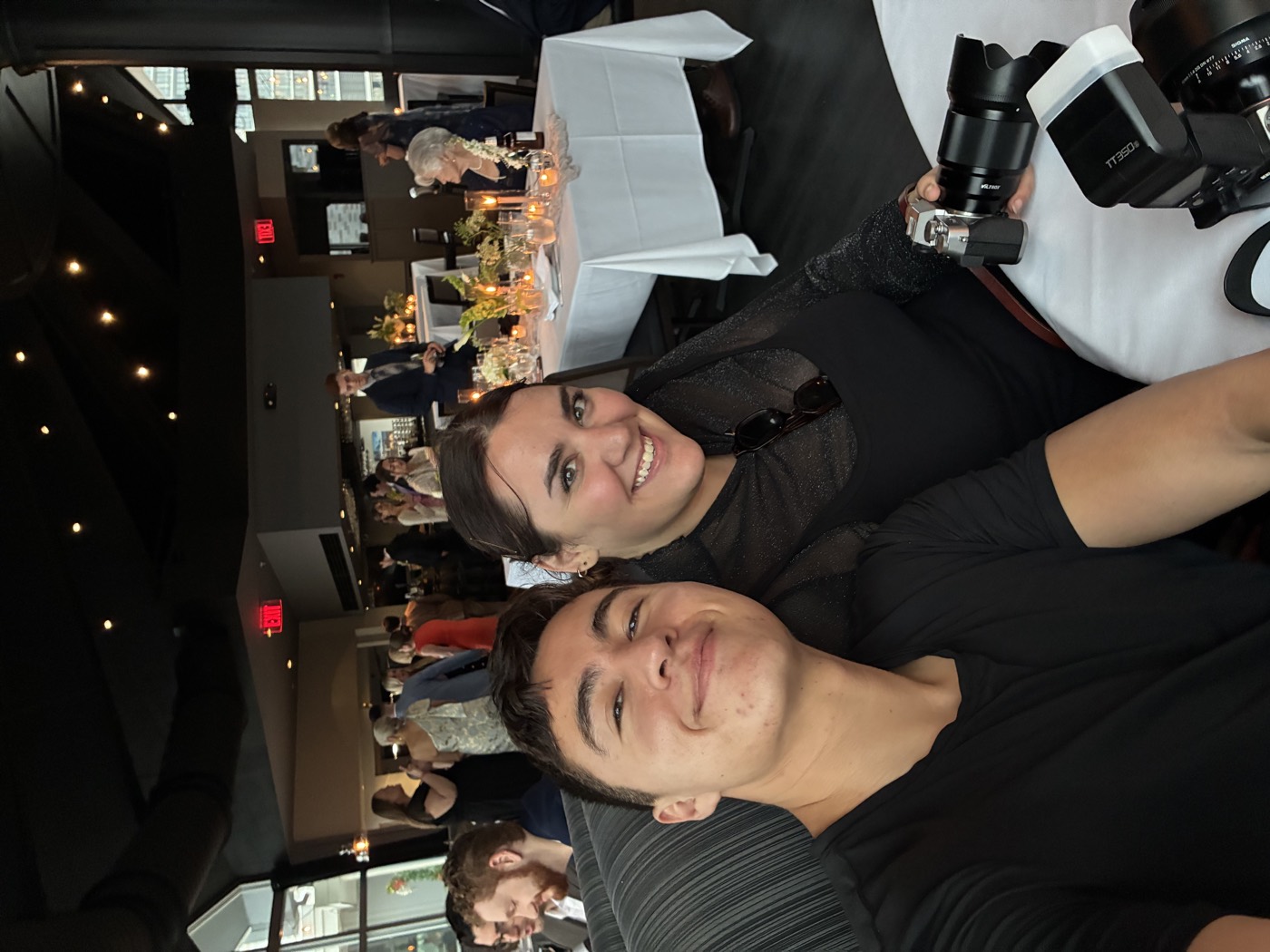 Cesar holding his camera rig at a wedding, grinning with a friend