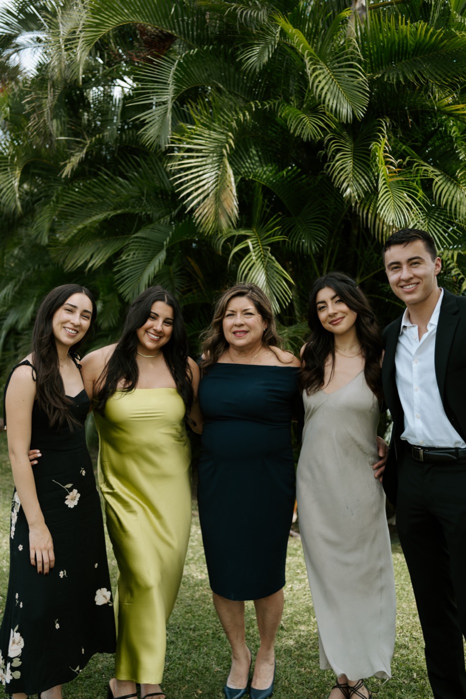 Cesar with his mom and three older sisters in front of palm trees