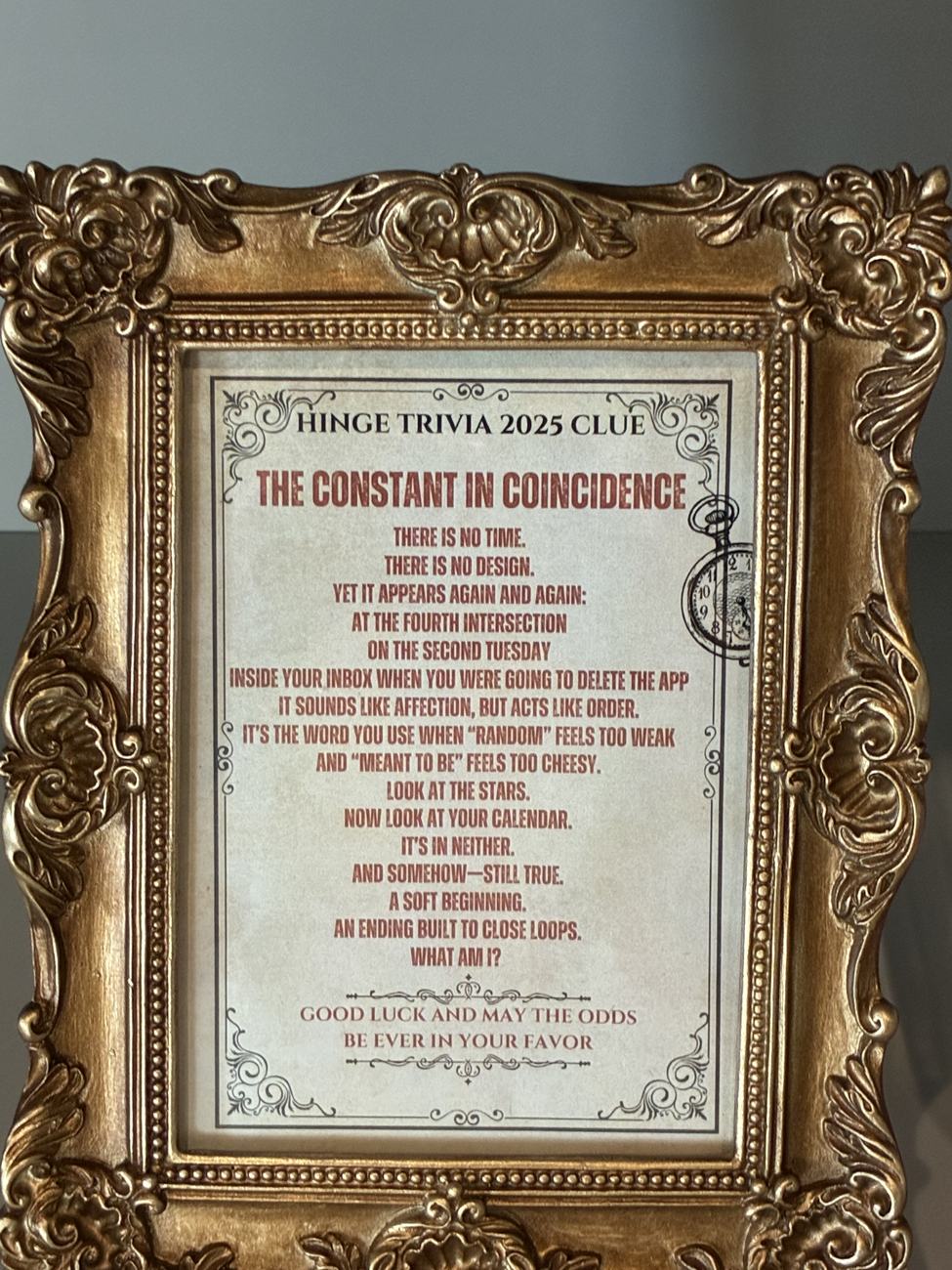 An ornate gold frame holding a printed trivia riddle titled The Constant in Coincidence